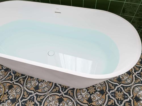 a white bath tub sitting on top of a tile floor at MADISON Saint Jean de Luz - Handwritten Collection in Saint-Jean-de-Luz