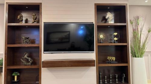 a entertainment center with a large television in a living room at Gold Crest Executive Hotel Apartments City View DHA Lahore in Lahore