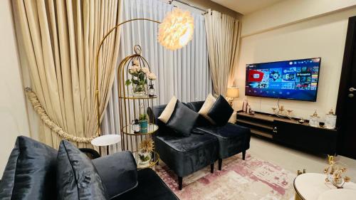a living room with a couch and a tv at Gold Crest Executive Hotel Apartments City View DHA Lahore in Lahore