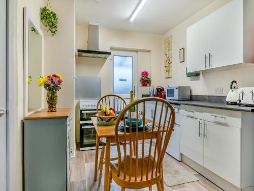 a kitchen with white cabinets and a table and chairs at The Lodge in Pauntley