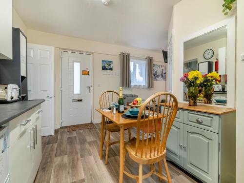 a kitchen with a wooden table and two chairs at The Lodge in Pauntley