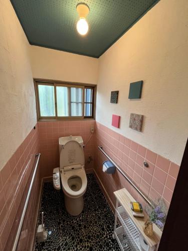 a bathroom with a toilet and pink tiles at 伊勢ブルーヴィラ本館と離れ in Ise