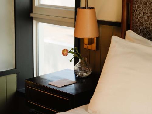 a table with a lamp and a flower on a bed at Balfour Miami Beach, a Morgans Originals hotel in Miami Beach