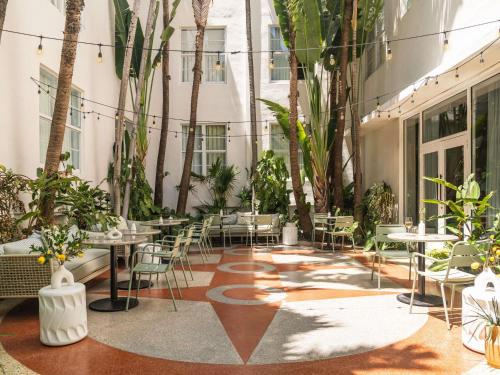 a courtyard with tables and chairs and palm trees at Balfour Miami Beach, a Morgans Originals hotel in Miami Beach