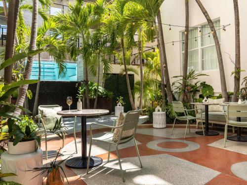 a patio with tables and chairs and palm trees at Balfour Miami Beach, a Morgans Originals hotel in Miami Beach