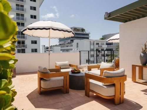a patio with chairs and a table and an umbrella at Balfour Miami Beach, a Morgans Originals hotel in Miami Beach