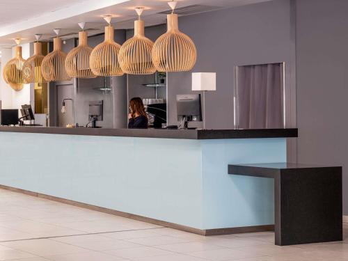 a woman sitting at a reception counter in a office at Hôtel Marseille Centre Gare Saint-Charles in Marseille