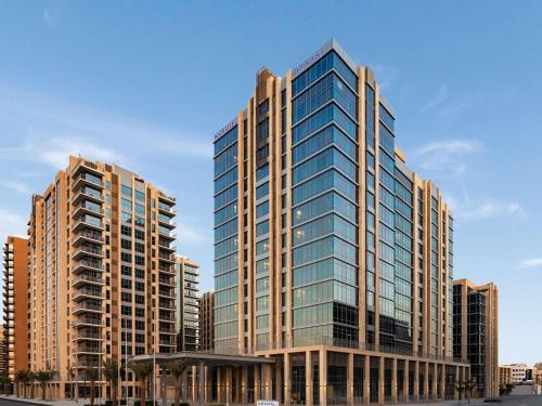 a tall building with glass windows in a city at Novotel Dubai Gold District in Dubai