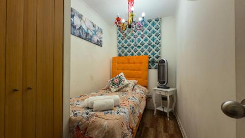 a small bedroom with a bed with an orange headboard at Metro Santa Ana 2 dormitorios wifi check in tardío in Santiago