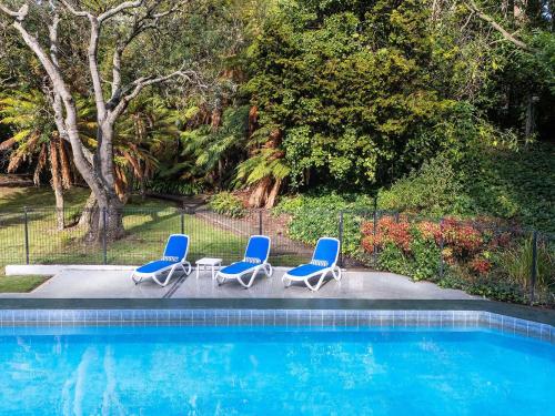 a group of three chairs and a swimming pool at Wairakei Resort Taupo in Taupo