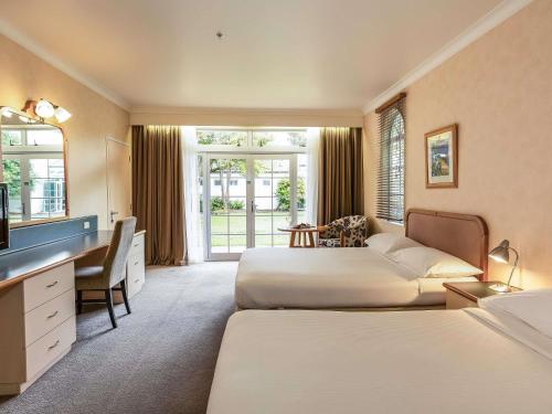 a hotel room with two beds and a desk at Wairakei Resort Taupo in Taupo