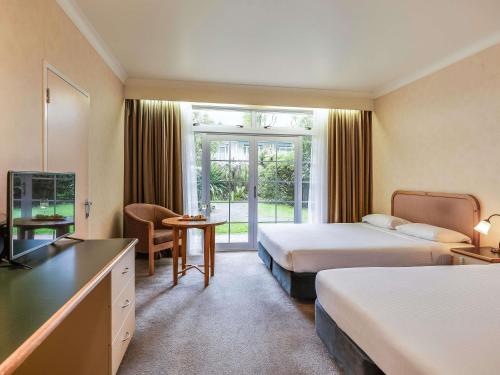 a hotel room with two beds and a television at Wairakei Resort Taupo in Taupo