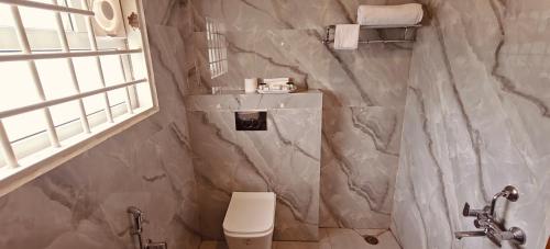 a bathroom with a toilet and a marble wall at Vintage Trails By Ilara in Alūr