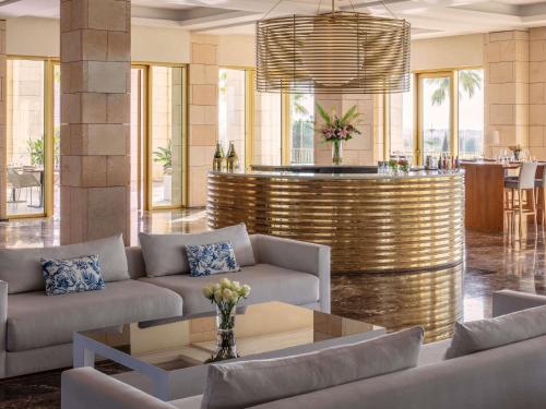 a lobby with couches and a bar in the background at Victoria Golf Resort and Spa Managed by Accor in Vilamoura