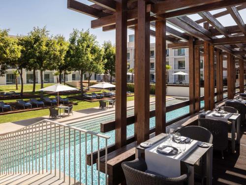 an outdoor patio with tables and chairs and a pool at Victoria Golf Resort and Spa Managed by Accor in Vilamoura
