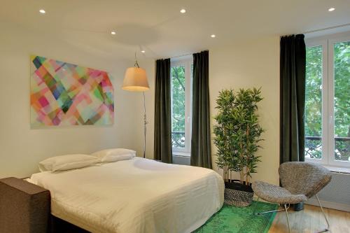 - une chambre avec un lit, une chaise et une plante dans l'établissement Pick A Flat's in Champs Elysees - Rue Percier, à Paris