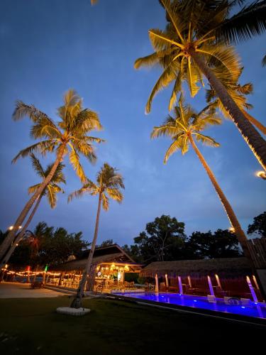 two palm trees in front of a building with blue lights at Chellie Rose Resort Hotel in Bantayan Island