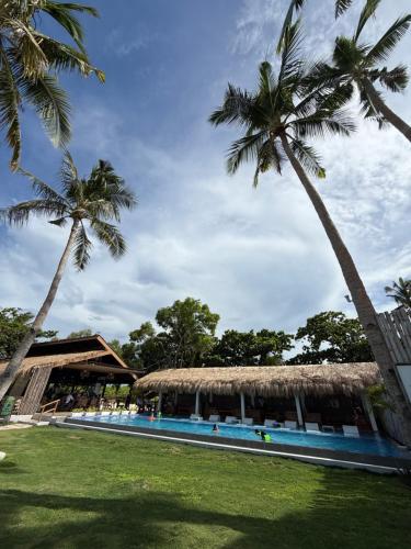 a resort with a swimming pool and two palm trees at Chellie Rose Resort Hotel in Bantayan Island