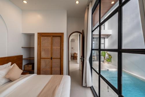 a bedroom with a bed and a swimming pool at Byjexa Villa by Betterplace in Uluwatu