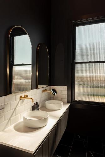 two sinks in a bathroom with two mirrors at The Victoria Hotel Rutherglen in Rutherglen