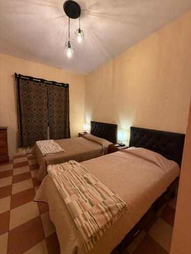 a bedroom with two beds and a checkerboard floor at Departamento ampliio y centrico 2 habitaciones con balcon in Orizaba