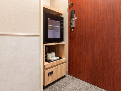 a room with a television and a wooden door at Hotel Villa Fontaine Tokyo-Jimbocho in Tokyo