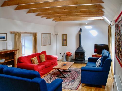 a living room with two red couches and a table at The Old Smiddy in Poolewe