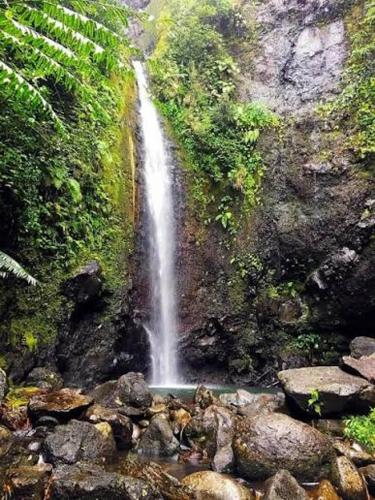 a waterfall on the side of a mountain with rocks at Apetahi - Bord de mer - in Opoa