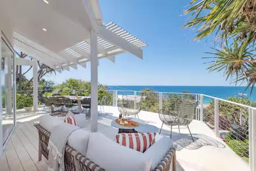 a patio with white furniture and the ocean in the background at Seaviews at Sunshine Beach 4BR, Pool in Sunshine Beach