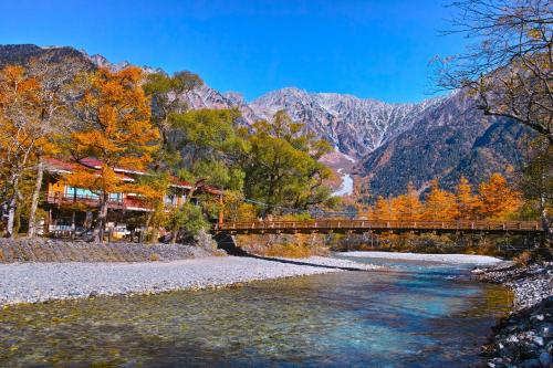a bridge over a river with mountains in the background at Private Retreat Nagano Iizuna 