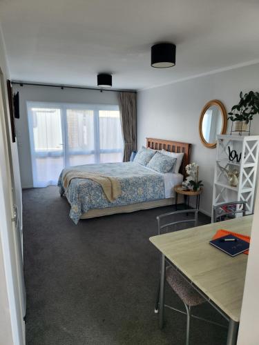 a bedroom with a bed and a table at Cosy Studio Unit on Longview in New Plymouth