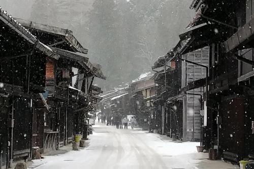 a snow covered street in a town with buildings at Private Retreat Nagano Iizuna 