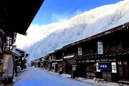 a snowy street with buildings and a mountain at Private Retreat Nagano Iizuna 