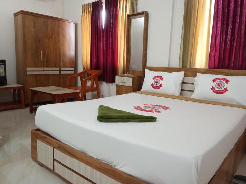 a bedroom with a large white bed with a green towel on it at Benzy Tourist Home in Ponnāni