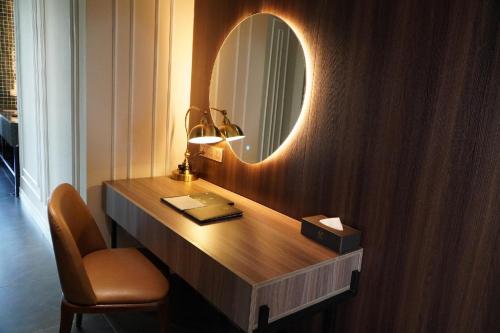 a bathroom with a vanity with a mirror and a chair at La Vela Hue Hotel in Hue