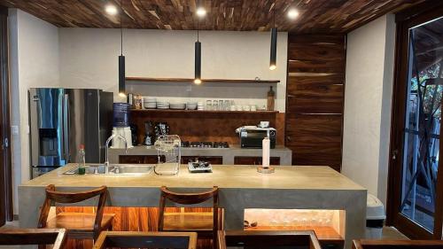 ChanoLuxury Dream Village in Palmarito Puerto Escondido的厨房设有大岛,配有椅子和柜台