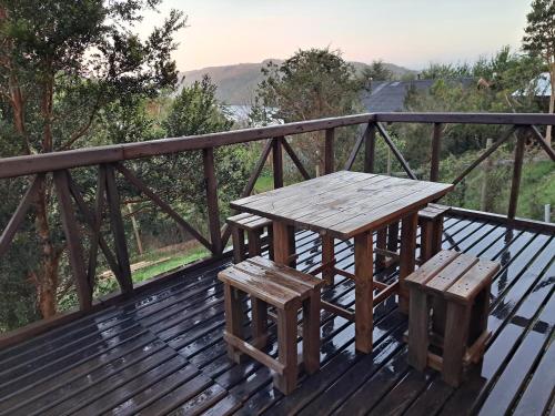 a wooden table and benches on a wooden deck at Cabaña Acogedora con Vista al Rio Valdivia, Niebla in Valdivia