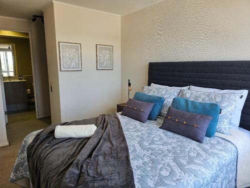 a bedroom with a large bed with blue pillows at Brisa del Sol, next to the airport & MDS Casino in Concepción