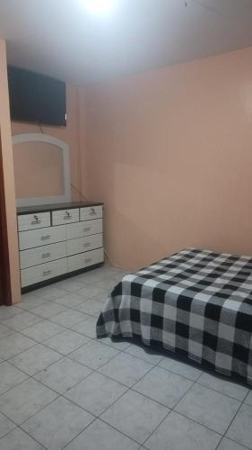 a bedroom with a bed and a dresser and a mirror at Artur House Alojamiento in Manta