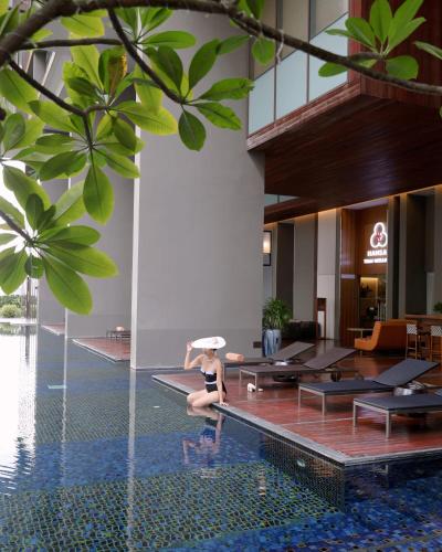 a woman sitting on the edge of a pool in a hotel at Hansar Bangkok Hotel in Bangkok