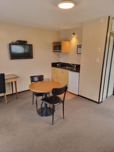 a room with a table and chairs and a kitchen at Broadway Motel in Picton