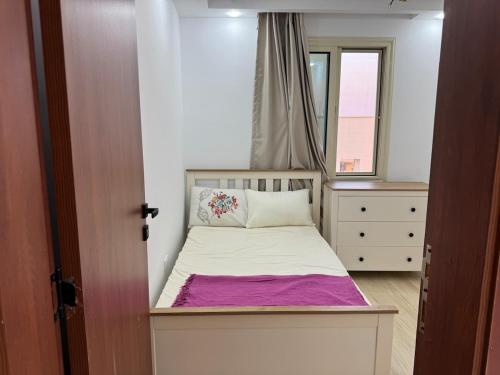 ein kleines Schlafzimmer mit einem Bett und einem Fenster in der Unterkunft رويال روف بالتجمع الخامس أمتداد الجامعة الامريكية in New cairo