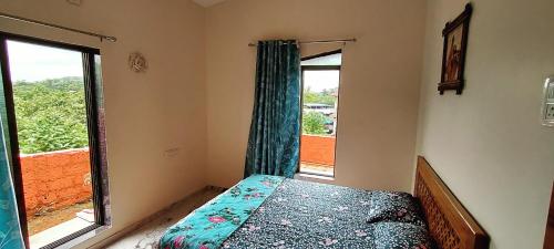 a bedroom with a bed and a large window at Harekar Holiday Homes in Dapoli