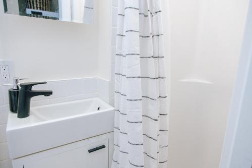 a white bathroom with a sink and a shower curtain at B Hotel in Toronto