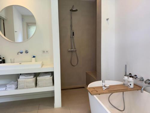 a bathroom with a tub and a sink and a mirror at Het Bosch in Bergen