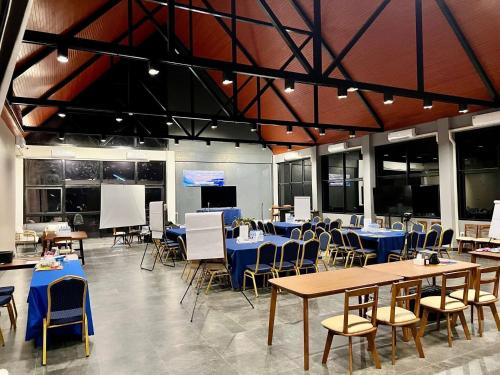 a dining hall with tables and chairs and a screen at GrandWara Khao Yai แกรนด์วารา เขาใหญ่ in Ban Nong Song Hong