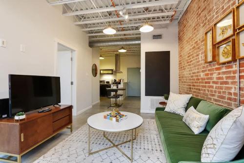 a living room with a green couch and a brick wall at Modern One Bedroom with Balcony in New Orleans