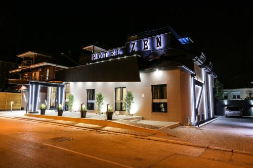 a hotel with a sign on the front of it at night at Garni Hotel Zen free parking in Niš