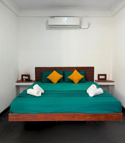 a bedroom with a green bed with yellow pillows at Jess Beach Villa in Galle