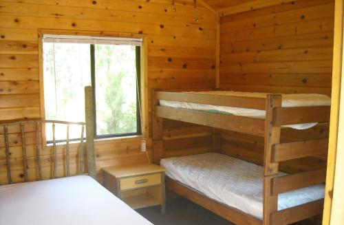 um quarto com 2 beliches num chalé de madeira em Yosemite Lakes Bunkhouse Cabin 27 em Harden Flat
